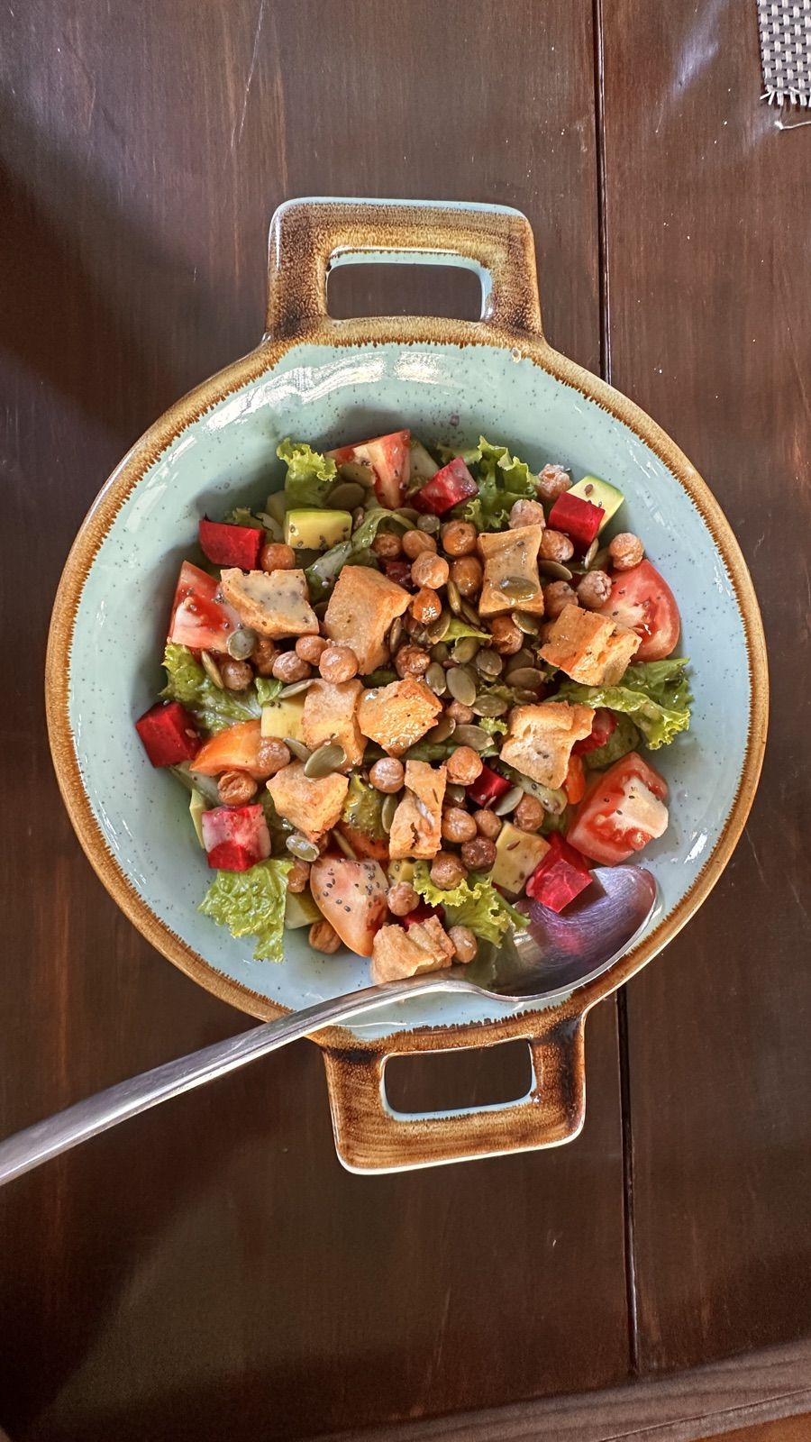 A salad with roasted chickpeas, croutons, avocado and seeds